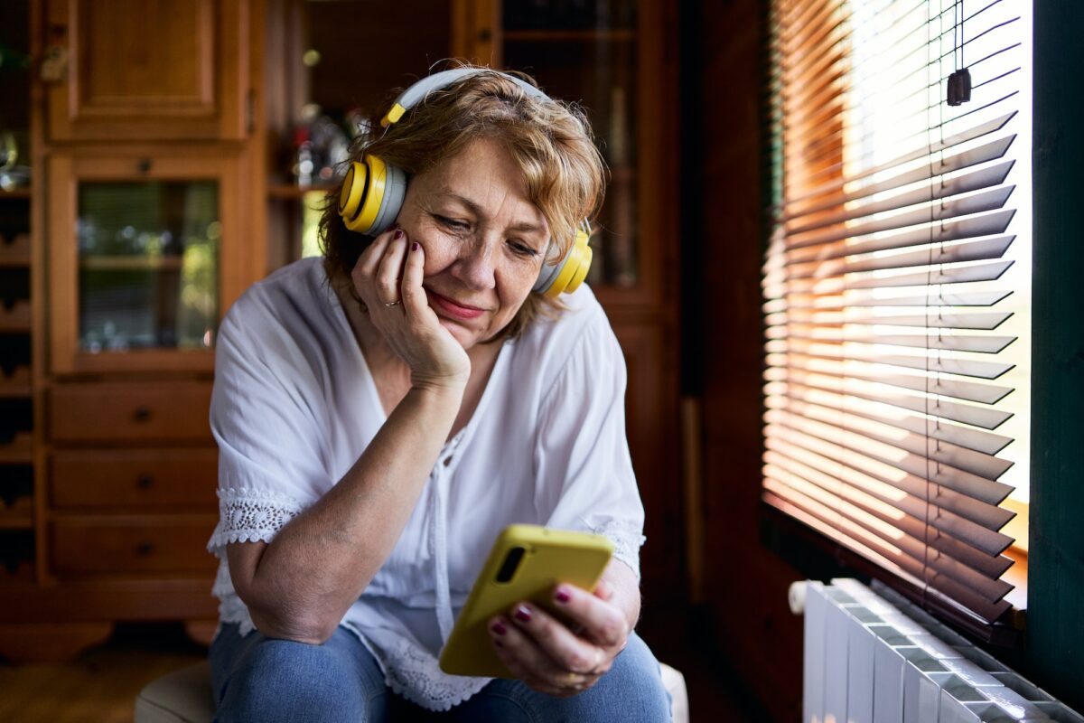 A mature woman thinking while listening to music on her cell phone at home