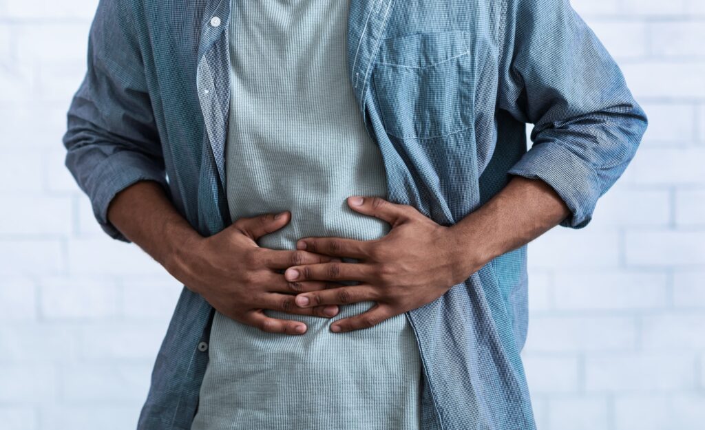 Black Guy Touching Aching Abdomen Having Stomachache, Gray Background, Cropped