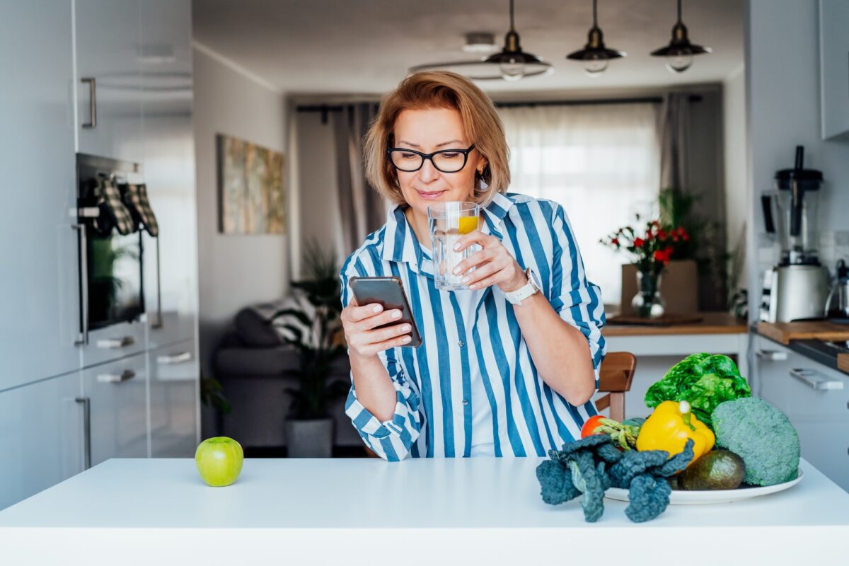 Healthy habit to drink water. Middle age woman drinking glass of pure water with lemon