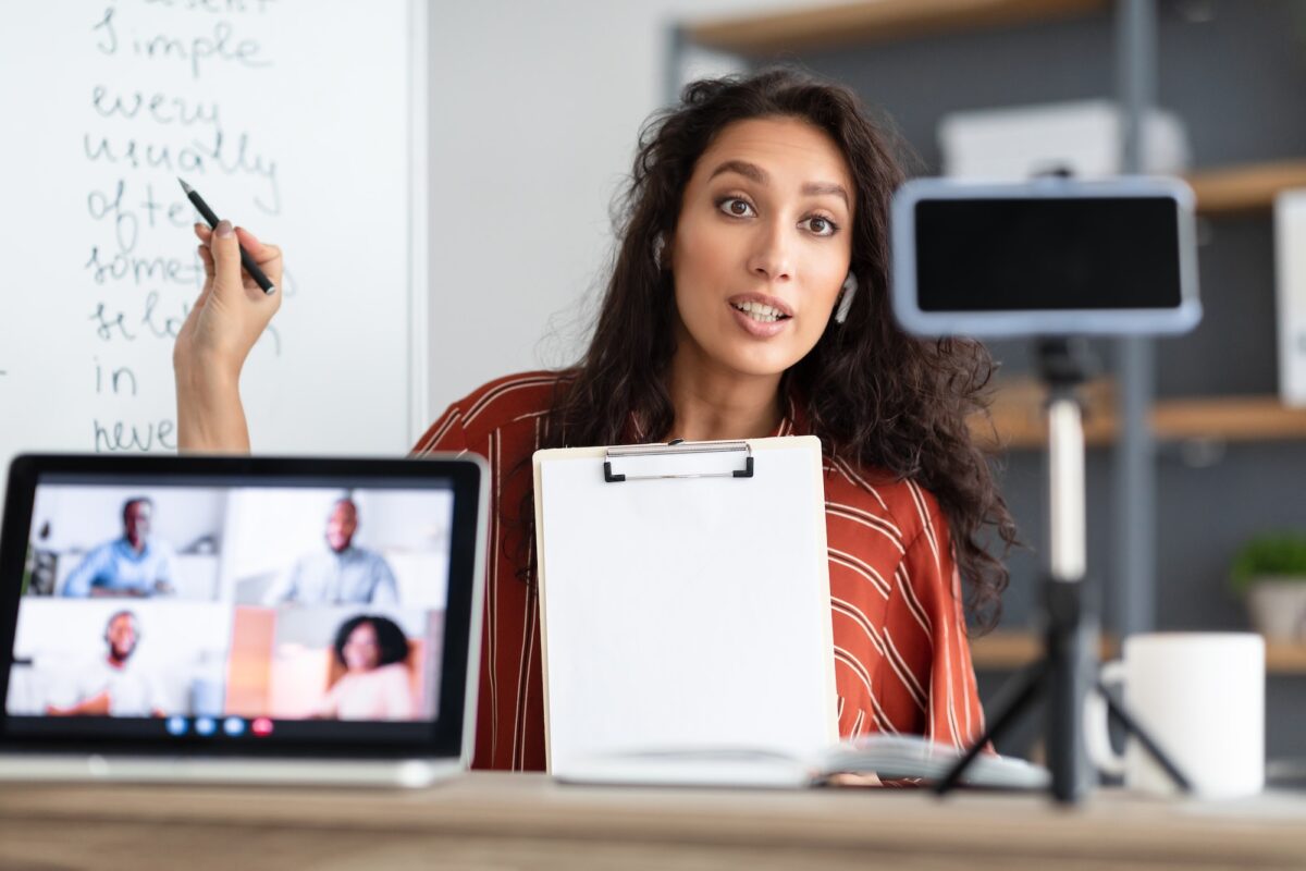 Young woman having video conference using phone and pc